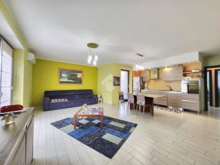 ampio salone living con cucina a vista ed accesso ai balconi